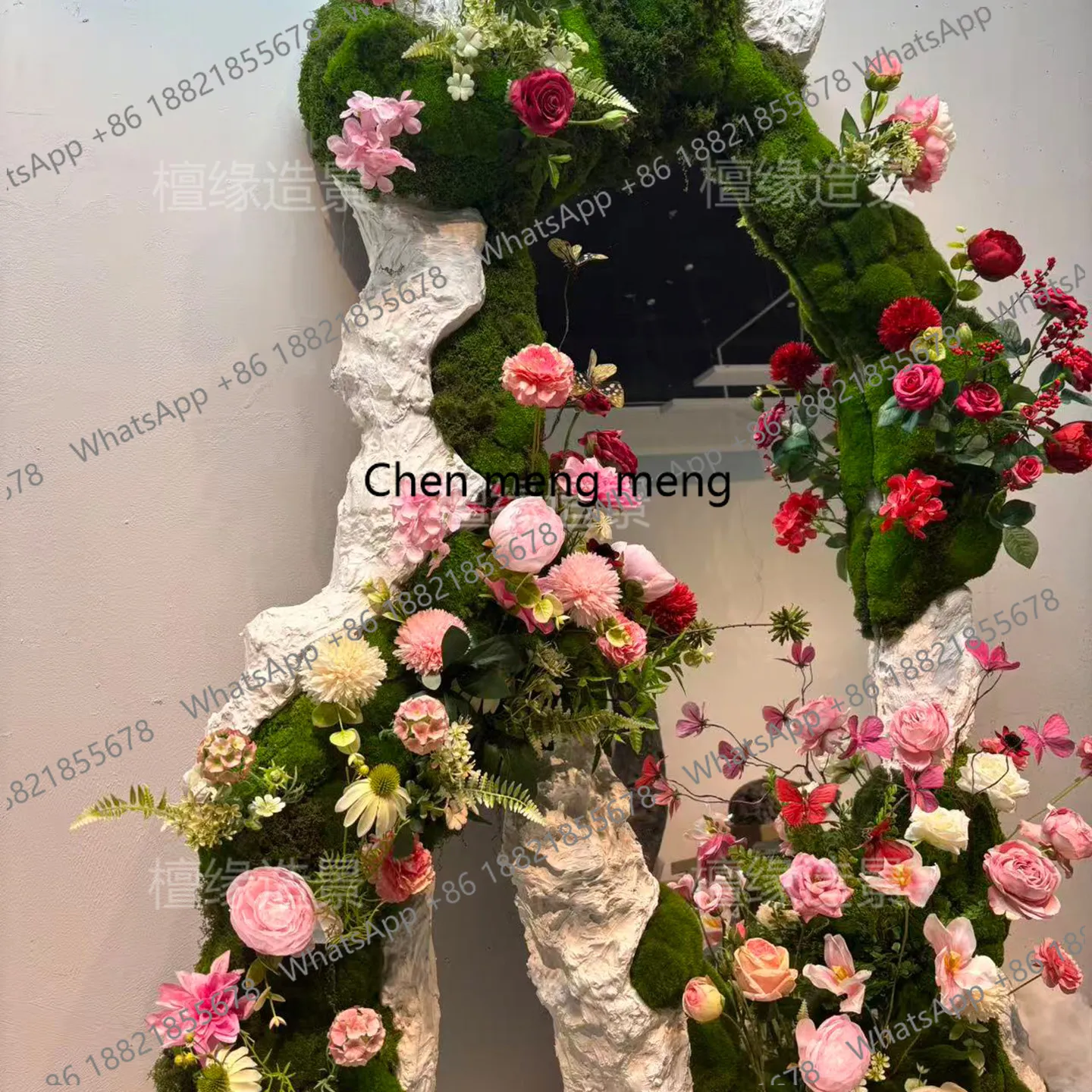 Baby Clothing Store - a55 衣料品店の窓の装飾鏡が緑の植物の壁を飾り、コーヒーショップの雰囲気には花飾りが配置されています。